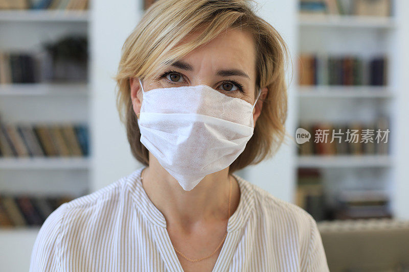 疫情期间居家佩戴医用口罩的中年妇女。