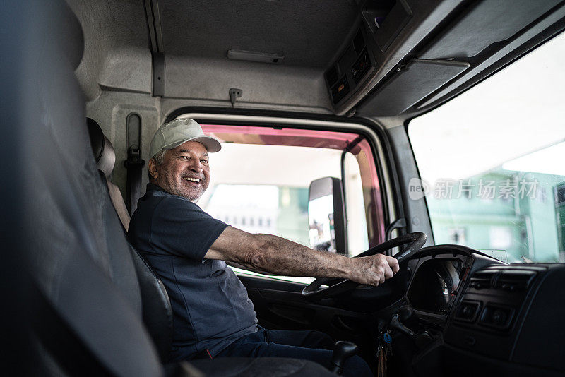 一位年长的男性卡车司机坐在驾驶室里