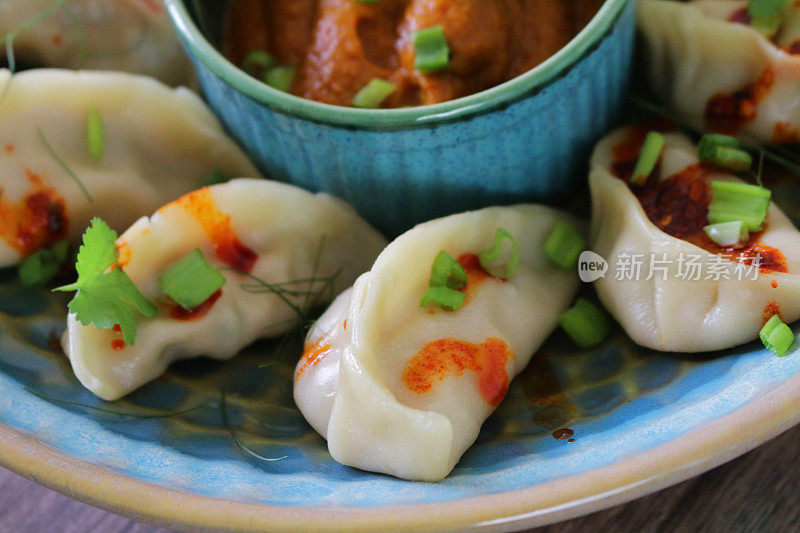 这是蒸过的馍馍(南亚饺子)，用白面粉和水面团填满鸡肉和什锦蔬菜，淋上辣椒油，放在盘子里，周围是用橙子辣酱做的小模子