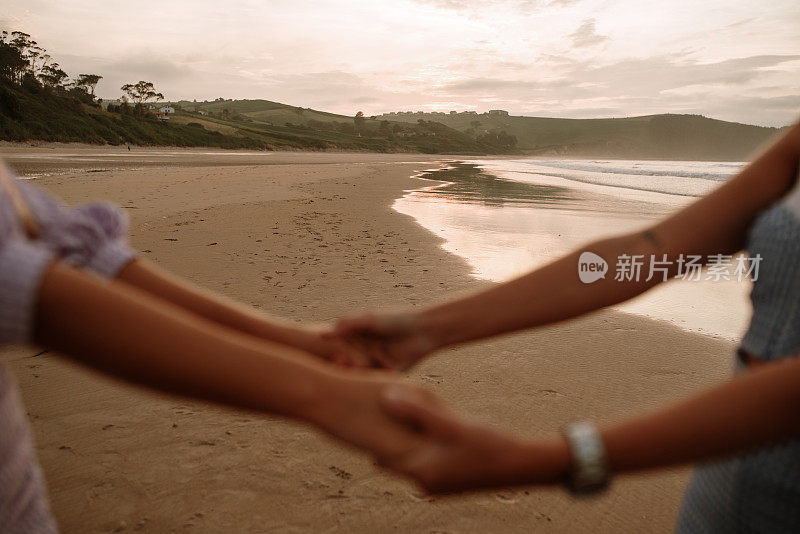 两个年轻女人在海滩上手拉手