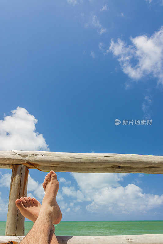 男性腿与游泳短天堂白沙热带海滩前绿松石海。