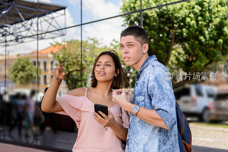 一对年轻夫妇在等一辆通过手机应用预订的出租车