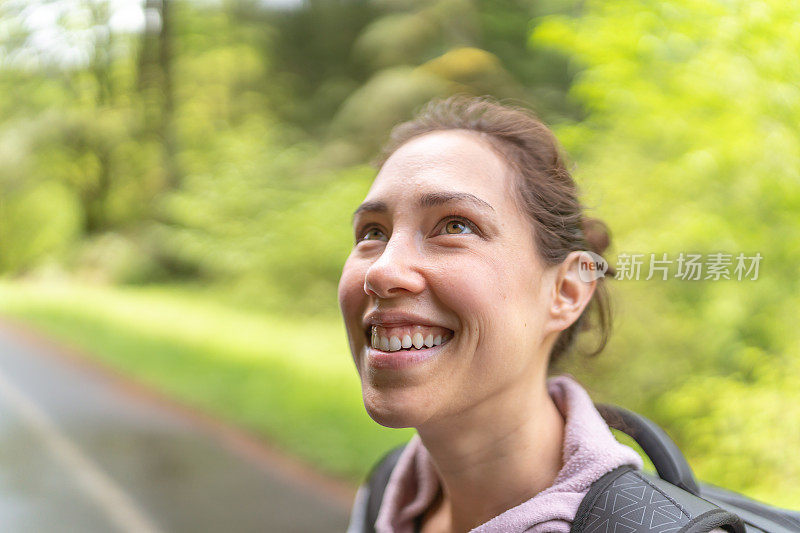 年轻的少数民族妇女走在路上，背着一个背包