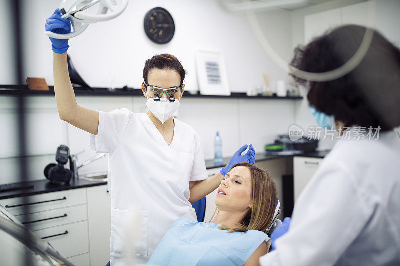 专业女牙医和她的助手在牙科诊所工作的病人。