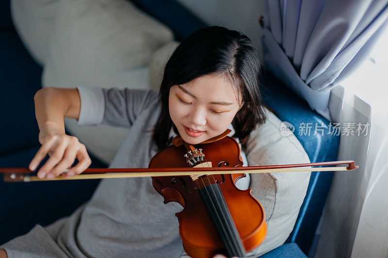 一位亚裔华裔女小提琴手在家里练习小提琴
