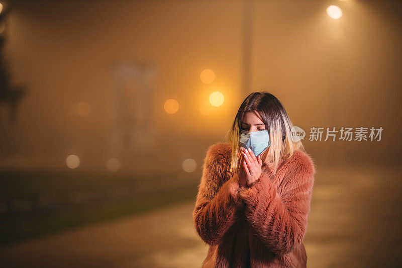 一个带着口罩的女人走在市中心，咳嗽着。被污染的空气。