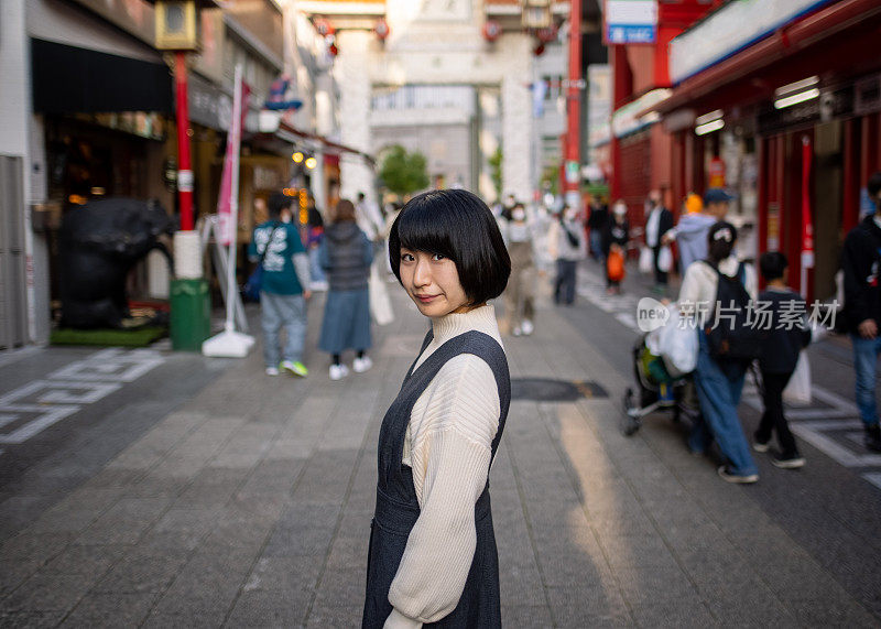 在中国城，日本神户，一个年轻的女人在街道的中央向后看