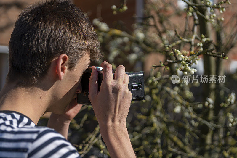 一个年轻人在花园里拿着一台老式的中画幅摄影机