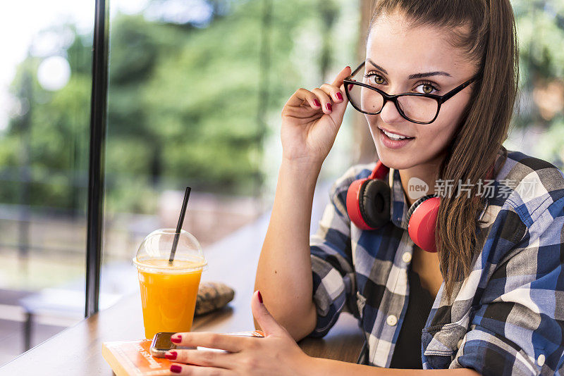 一个年轻漂亮的女人在咖啡店喝果汁。