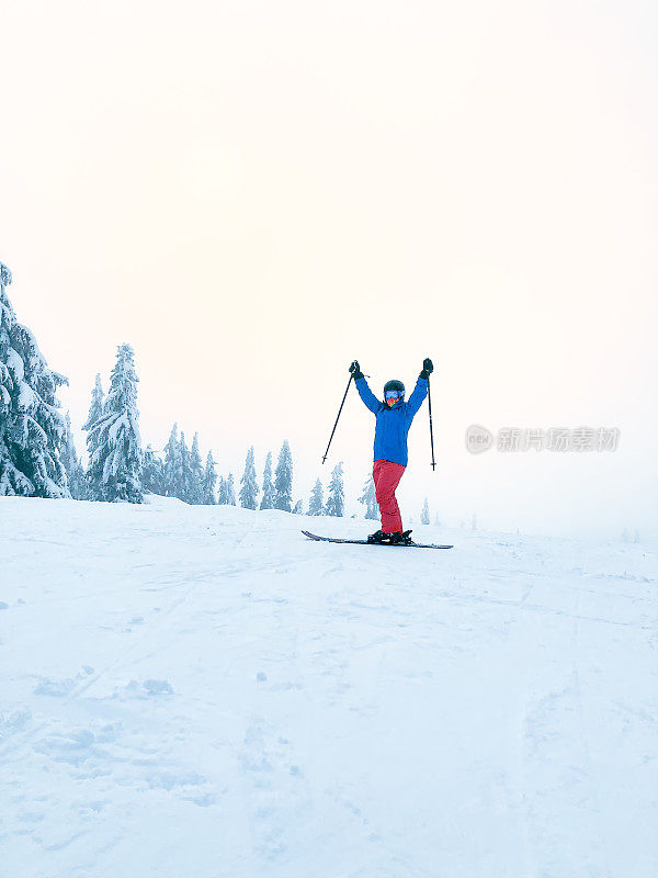 举起手臂的女子滑雪者，戴头盔和脖子绑腿