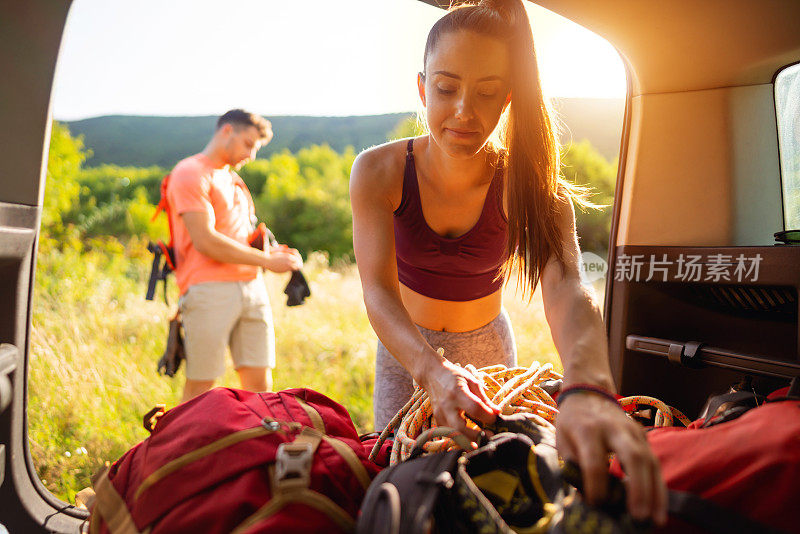 一名女性登山者在男友等待时将登山装备装进背包