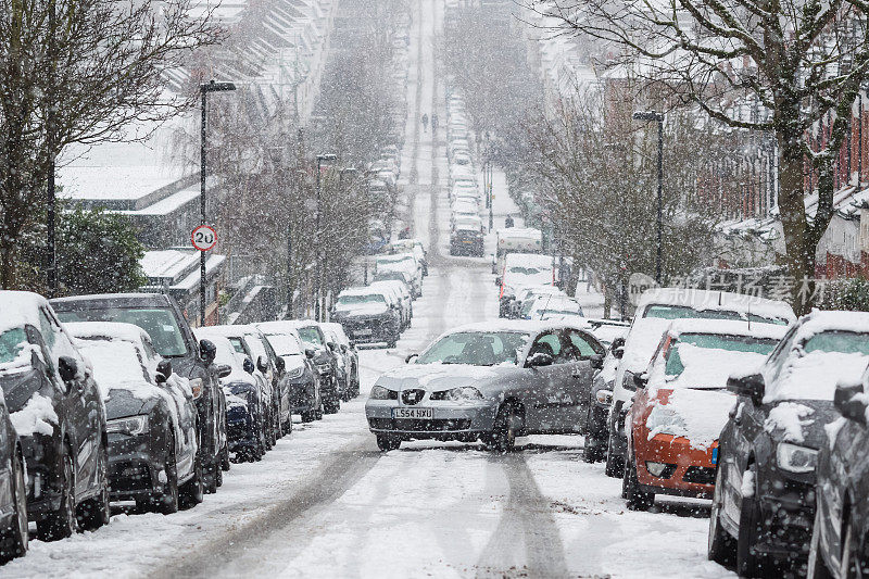 在恶劣的驾驶条件下，一辆汽车在伦敦克劳奇尽头的结冰道路上进行平行停车操作