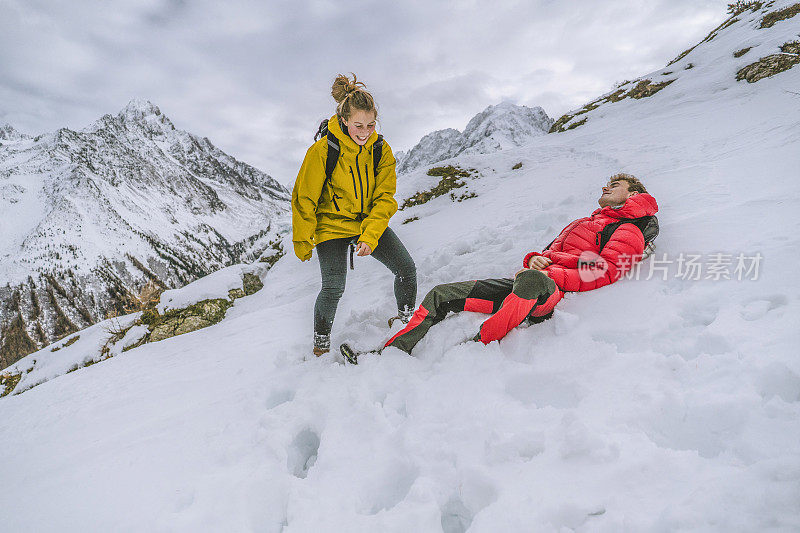 一对年轻的徒步旅行者在白雪皑皑的山脊上嬉戏