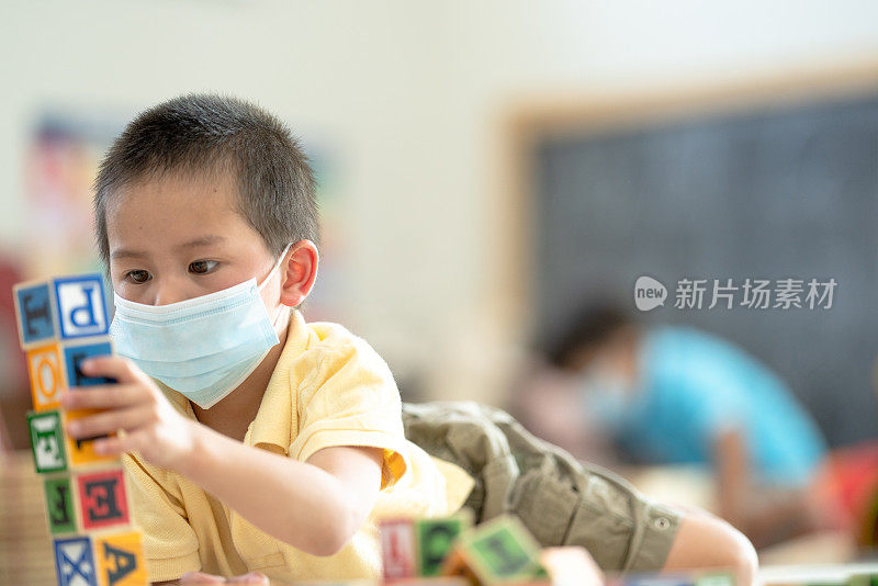 幼儿园男孩戴着面具在教室里的照片