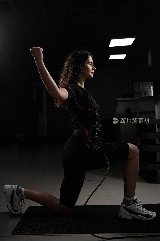健身房里穿着急救服的女孩，穿着肌肉电刺激服进行运动训练。