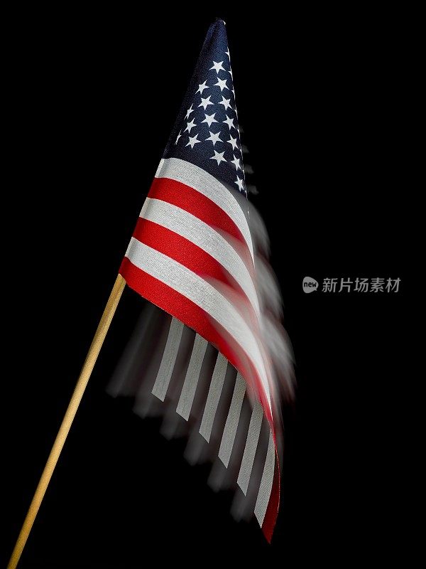 黑色背景的木制旗杆的美国国旗在微风中飘扬