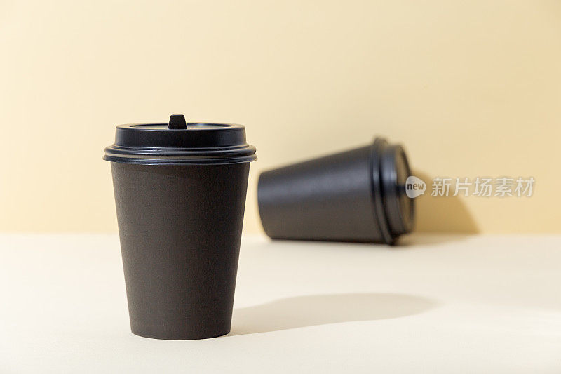 黑色纸杯，米色背景，用来装咖啡和茶。