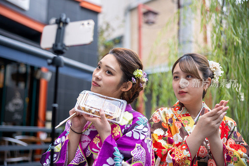 穿着和服的年轻女性在观光景点拍摄美食视频报道