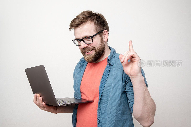 好主意。一个心满意足的男人手里拿着一台笔记本电脑，他有一个解决问题的办法，他举起手指，有趣地看了看。