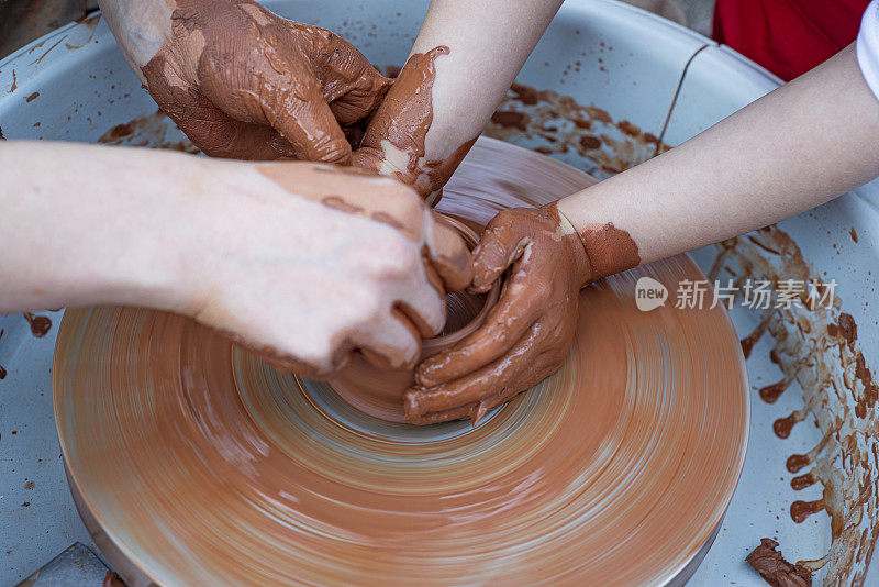 一个特写垂直拍摄的一个女孩和一个陶瓷车间教师与陶工的转盘工作