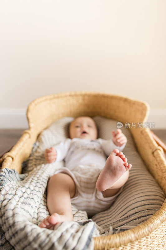 一个19周大的男婴的脚，有12个脚趾，躺在一个舒适的纱布毛毯在海草摩西篮子