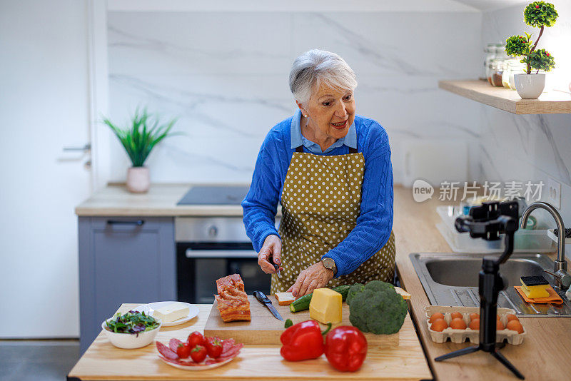 妇女准备食物配方，同时在线流与移动智能手机摄像头为网络厨房大师班频道