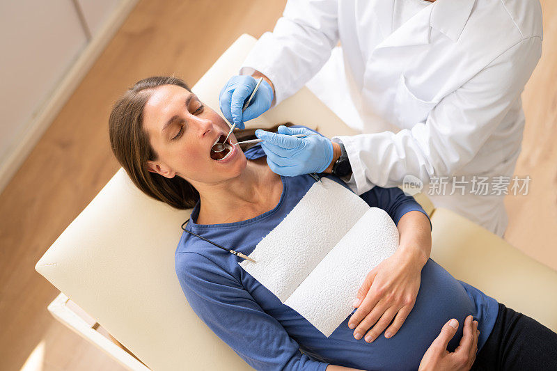 男性牙医治疗年轻孕妇的牙齿