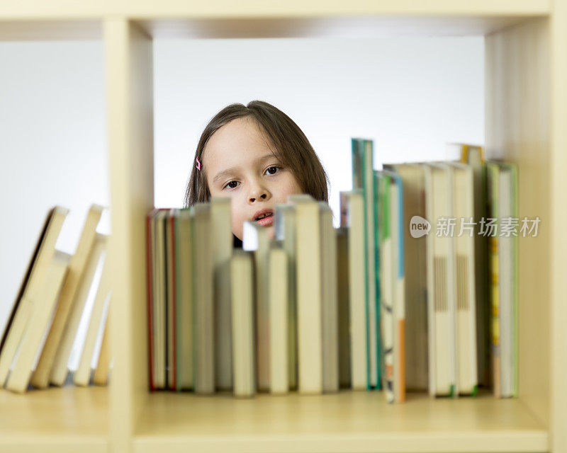 年轻的女孩在看书架上的书