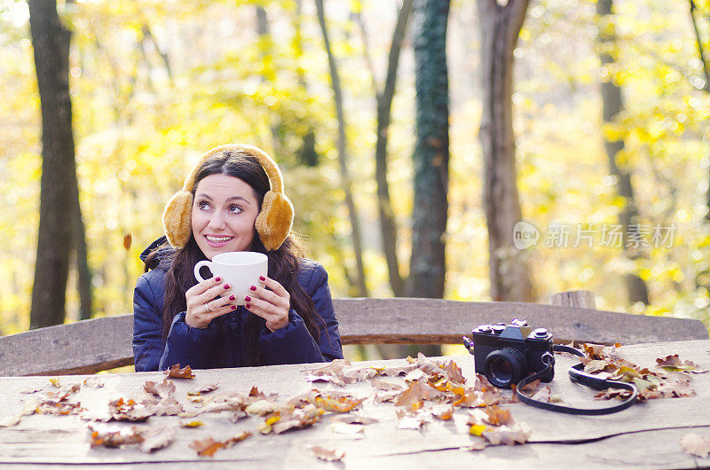 秋天的女人在秋天的森林里喝咖啡