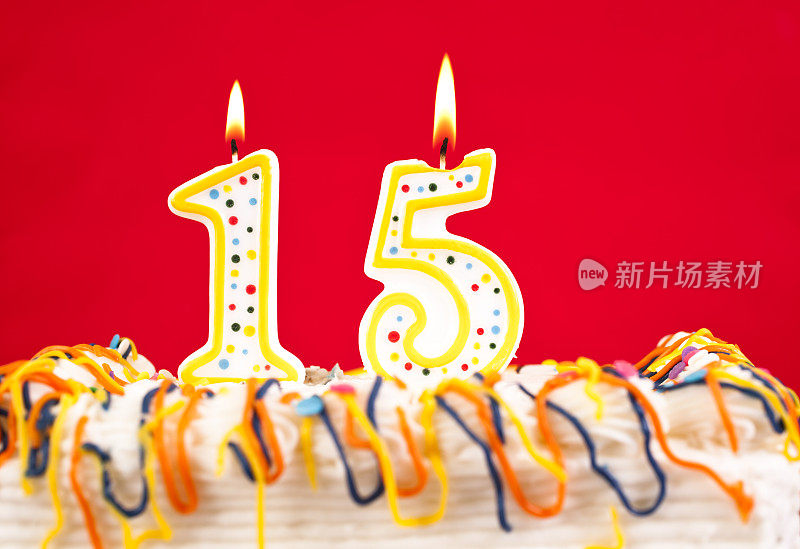 用15号燃烧的蜡烛装饰生日蛋糕。红色的背景。
