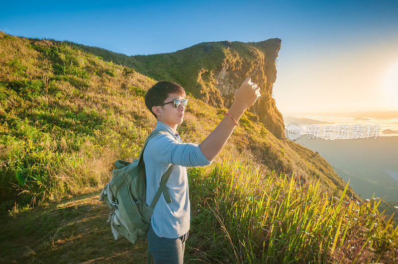 年轻的旅行者站在山上望着夕阳。