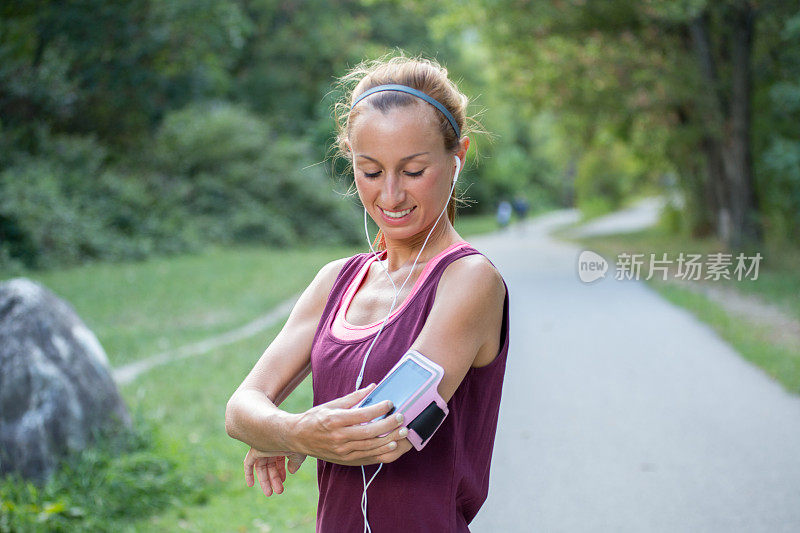 迷人和运动的年轻女子开始她的音乐播放列表户外