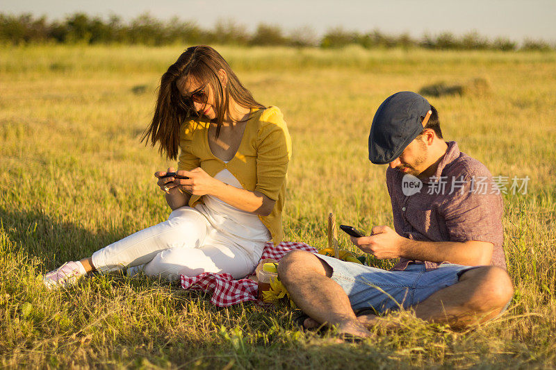 带着手机在草地上的一对夫妇