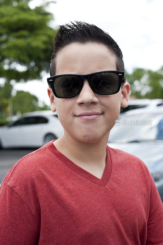 一个微笑的小男孩戴着他的太阳镜的肖像
