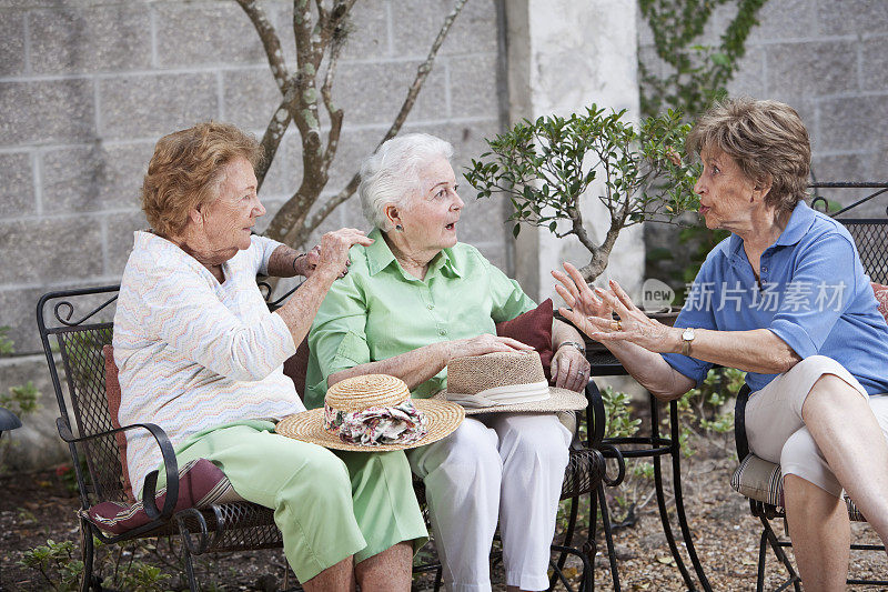 三位老妇人坐在院子里
