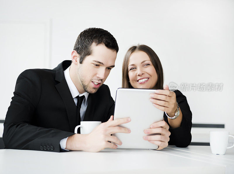 两个人在喝咖啡的时候拿着平板电脑