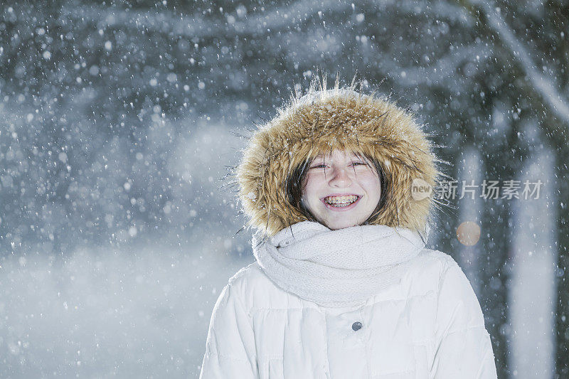 雪下穿着白色夹克的漂亮少女