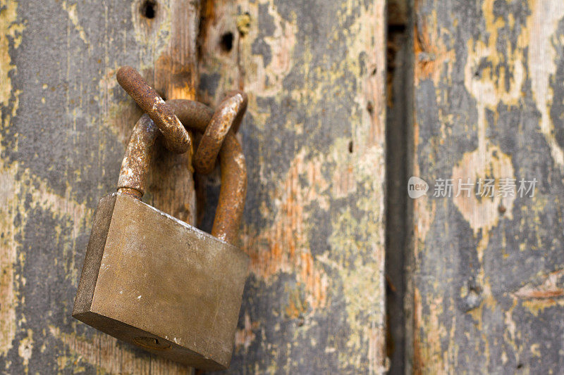 旧木门上生锈的旧青铜挂锁(特写)