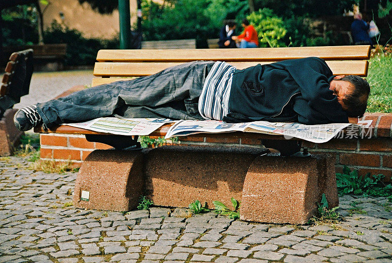 一个睡在公园长椅上的流浪汉