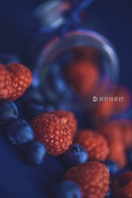 充满活力的有机树莓和蓝莓从玻璃罐中溢出