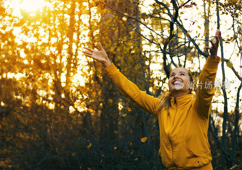 快乐的女人穿过阳光灿烂的森林