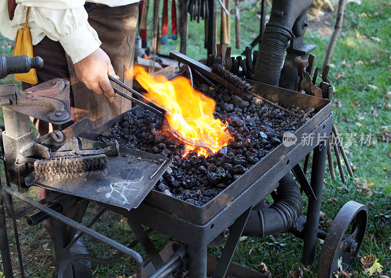 铁匠用钳子把马蹄铁夹在火里。