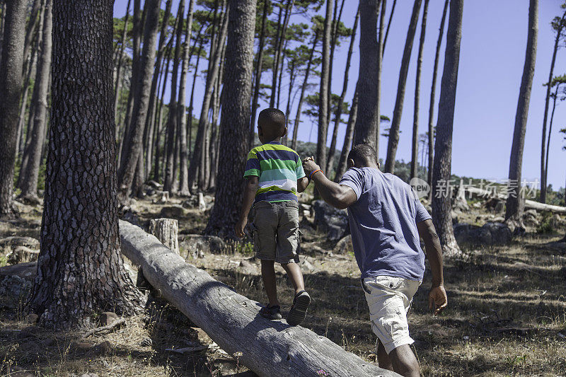 一位非洲父亲帮助儿子在圆木上行走
