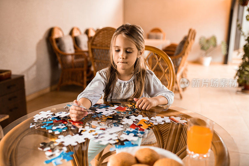 小女孩在桌子上玩拼图游戏。