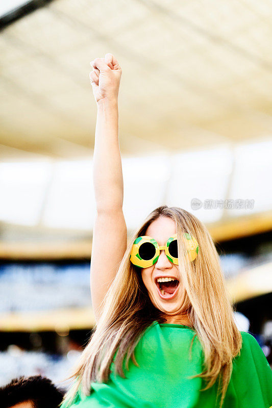 欣喜若狂的女足球迷在比赛时兴奋地叫喊和挥手
