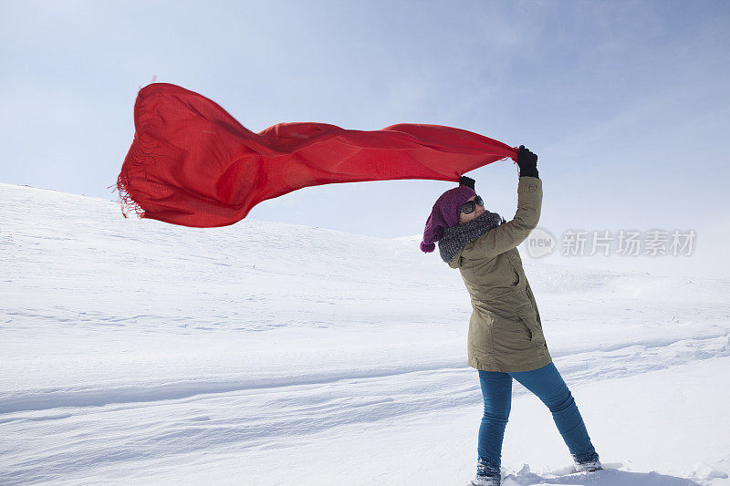 在雪风中拿着红围巾的年轻女子