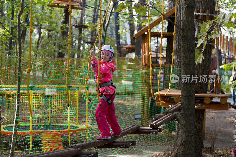 十几岁的女孩有乐趣在绳索课程冒险公园。Zipline为孩子。