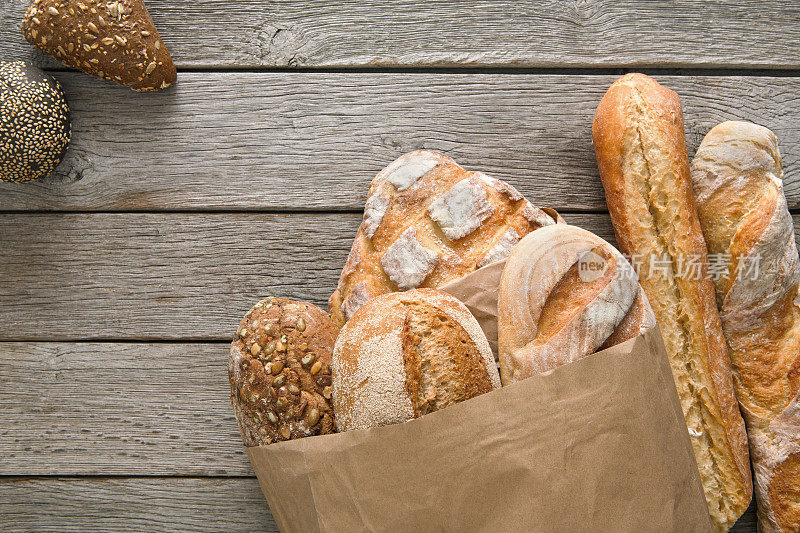 面包烘焙的背景。在乡村木材上的棕色和白色小麦谷物制成的面包