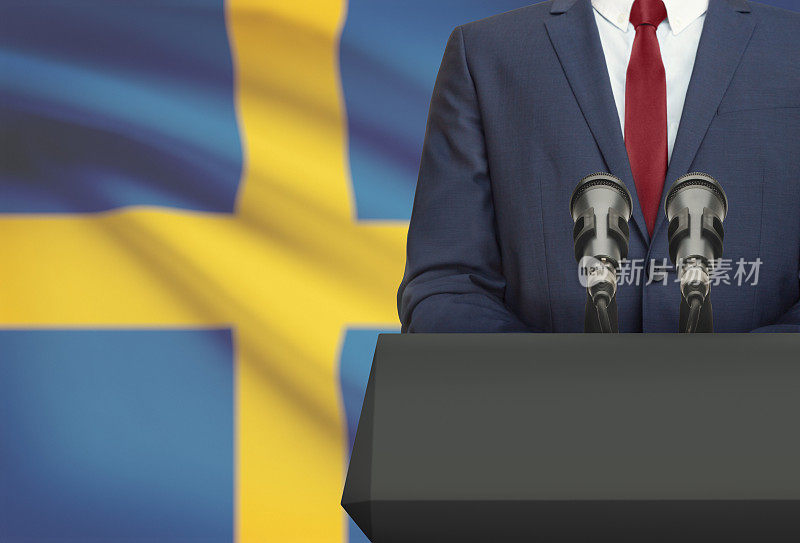 商人或政治家在讲坛后面发表演讲，背景是瑞典国旗