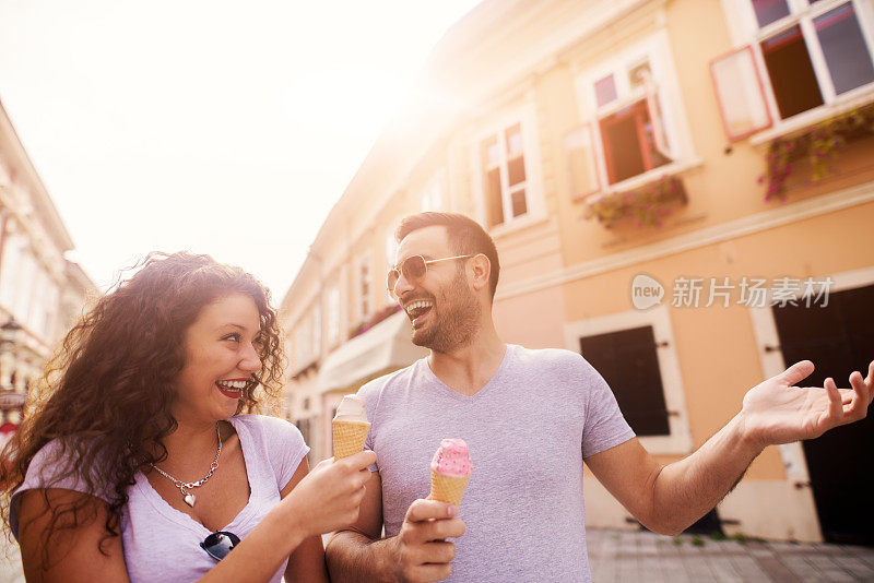 年轻幸福的夫妇在城市里享用冰淇淋和夏天。